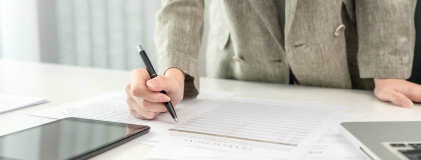 Mitarbeiterin mit Stift, Laptop, Unterschrift